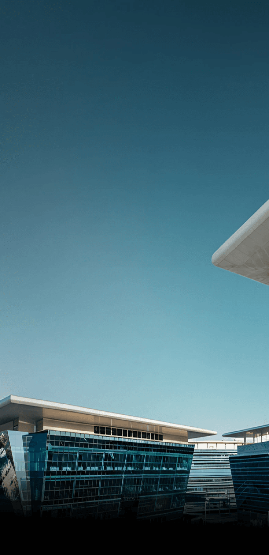 Dubai South Business Hub Free Zone - Modern building architecture with glass walls and geometric design under a clear sky.