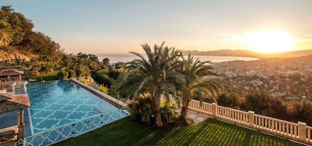 A mosaic-tiled pool and tall palm at Villa Alang Alang, on the terrace above Cannes at sunset.