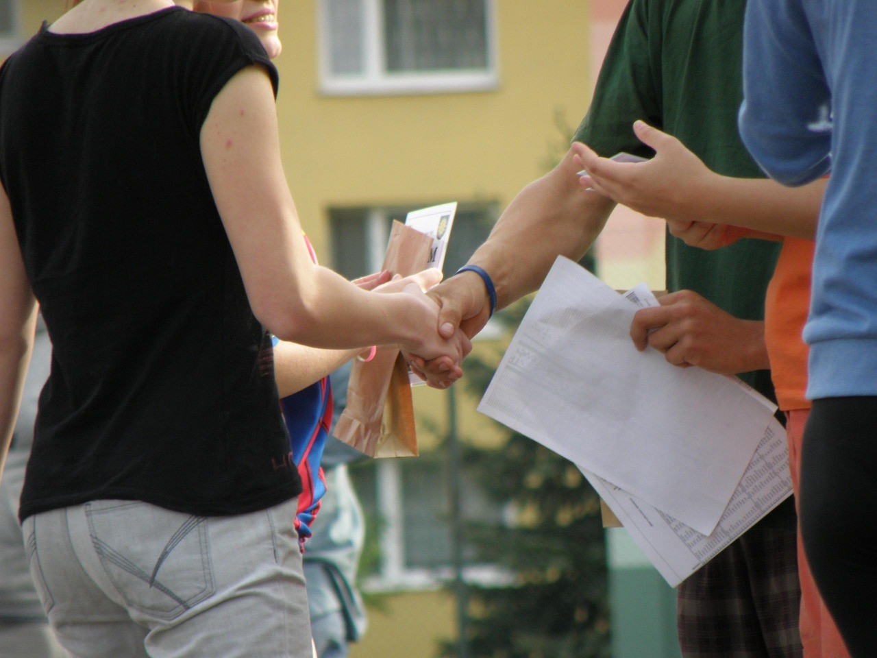 Personen beim Händeschütteln und Dokumente teilen, Teamwork im Freien
