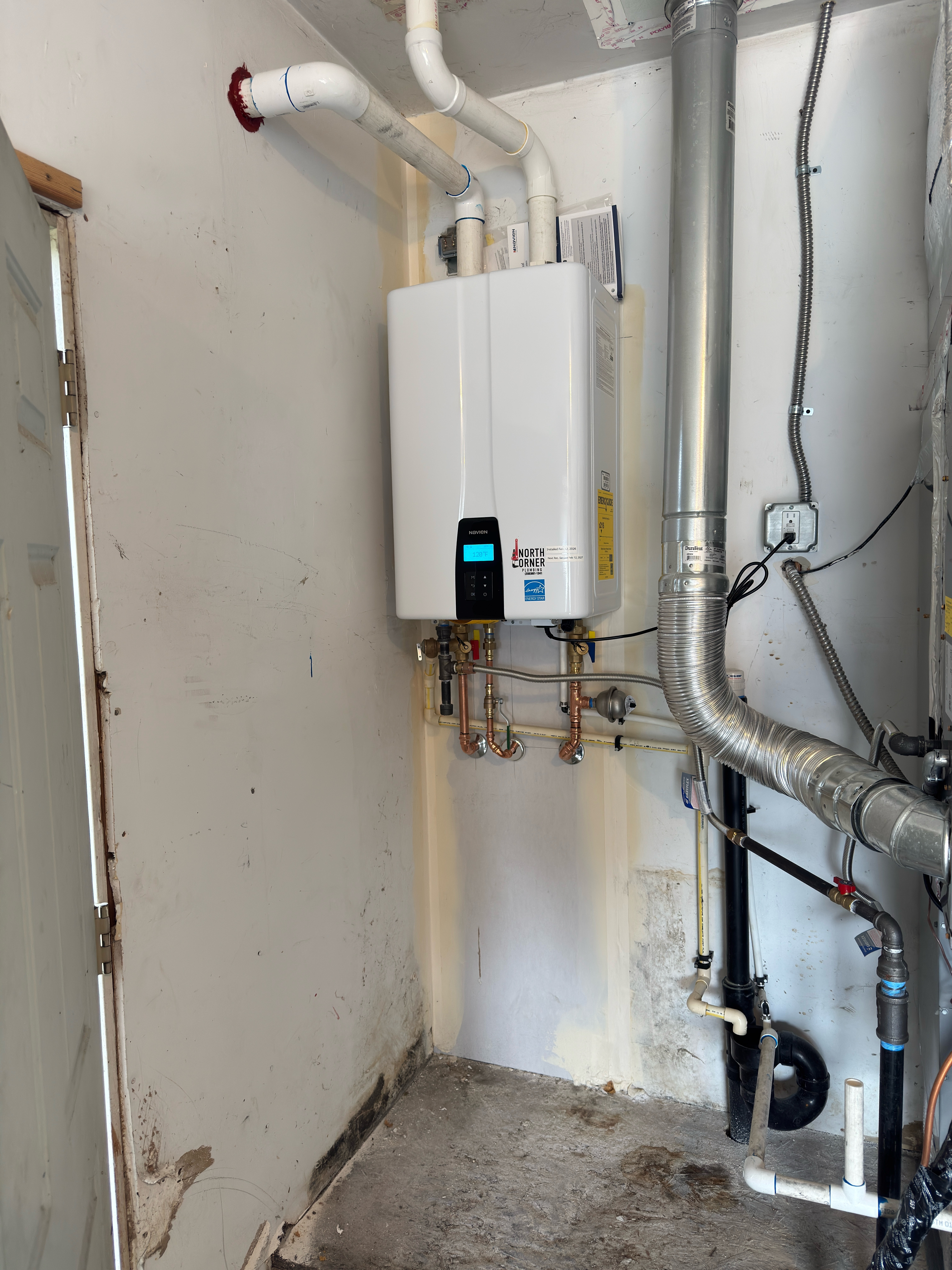 A smiling woman with her arms crossed, standing against a dark green background. She has long, dark hair.