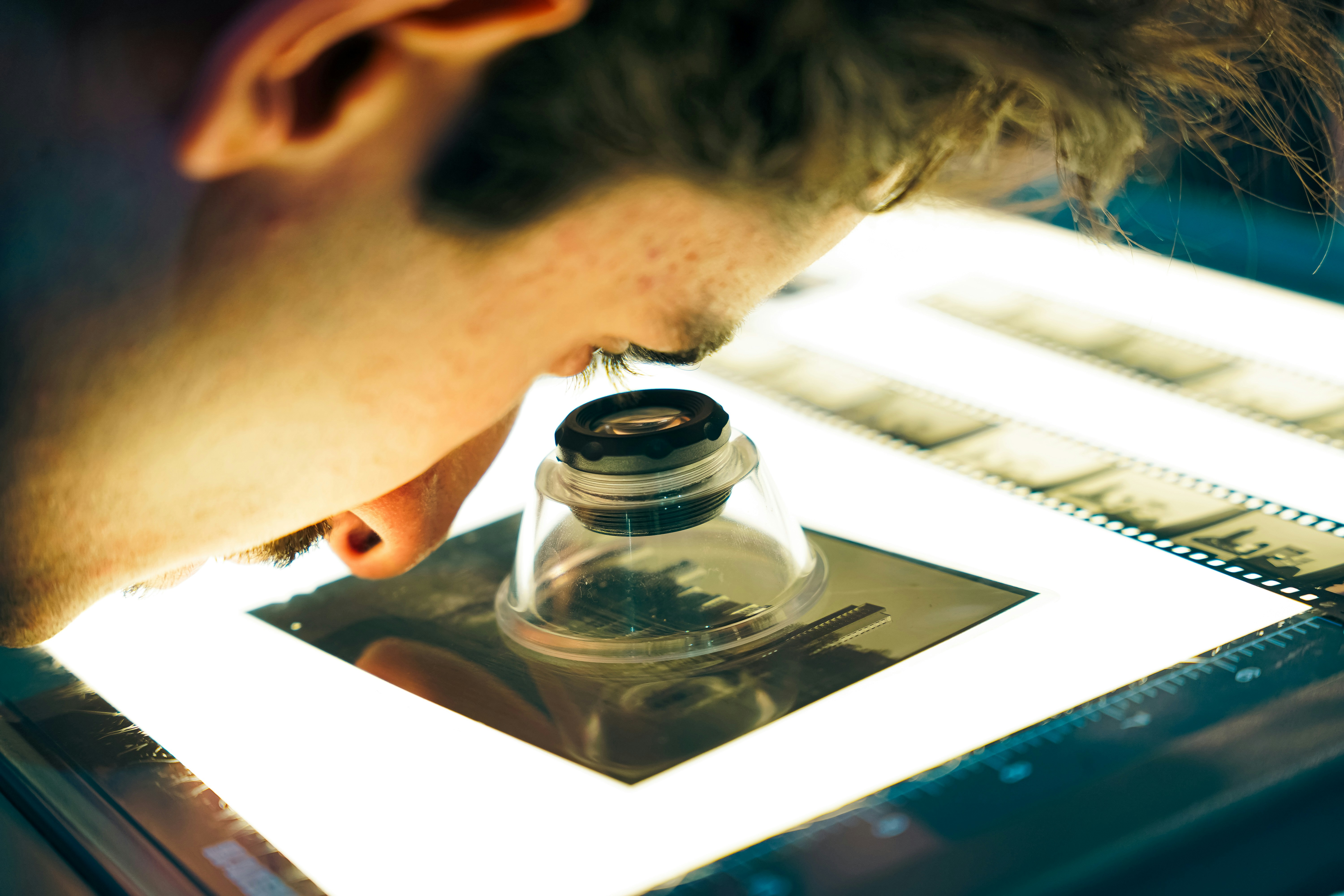 Person examining film negatives with a loupe.