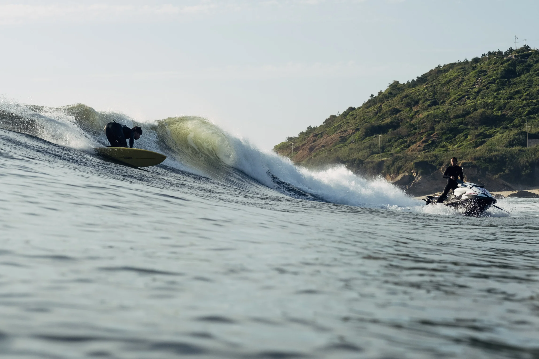 a person riding a jet ski on a body of water and a surfer