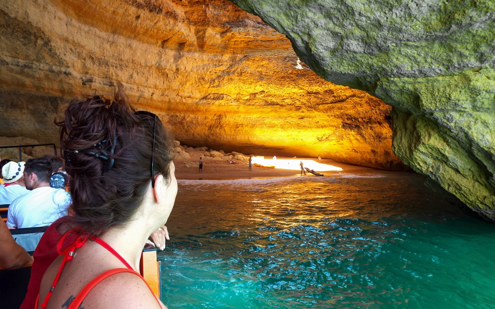 Passeio de barco guiado dentro das Cavernas de Benagil com pessoas admirando o interior iluminado da caverna.