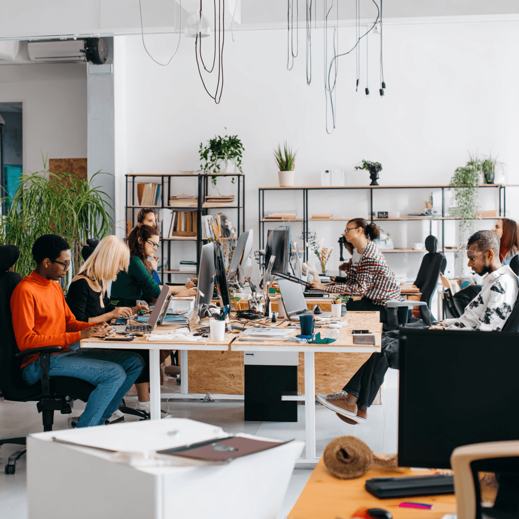 Two men discuss a project while standing at a laptop in an office.