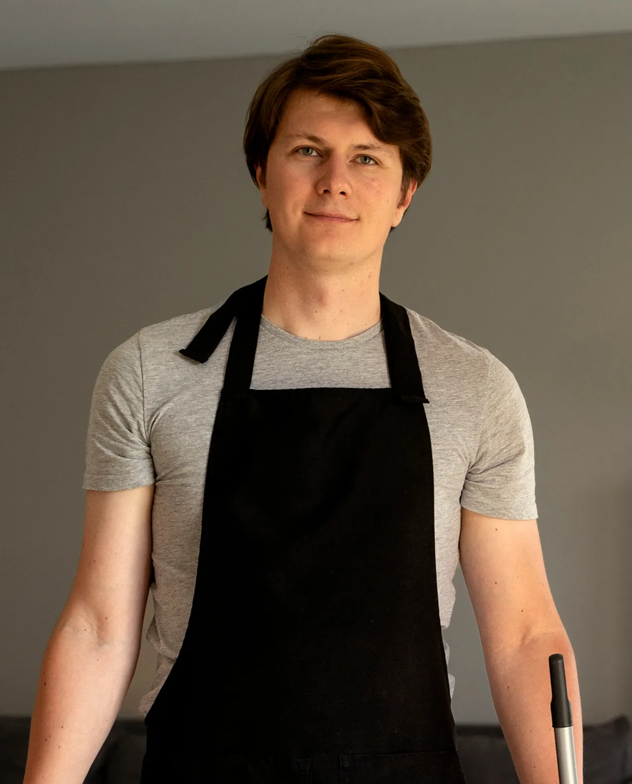 Junior Cleaner Adam Mike posing in a black apron, representing 3 years of experience in commercial cleaning services.