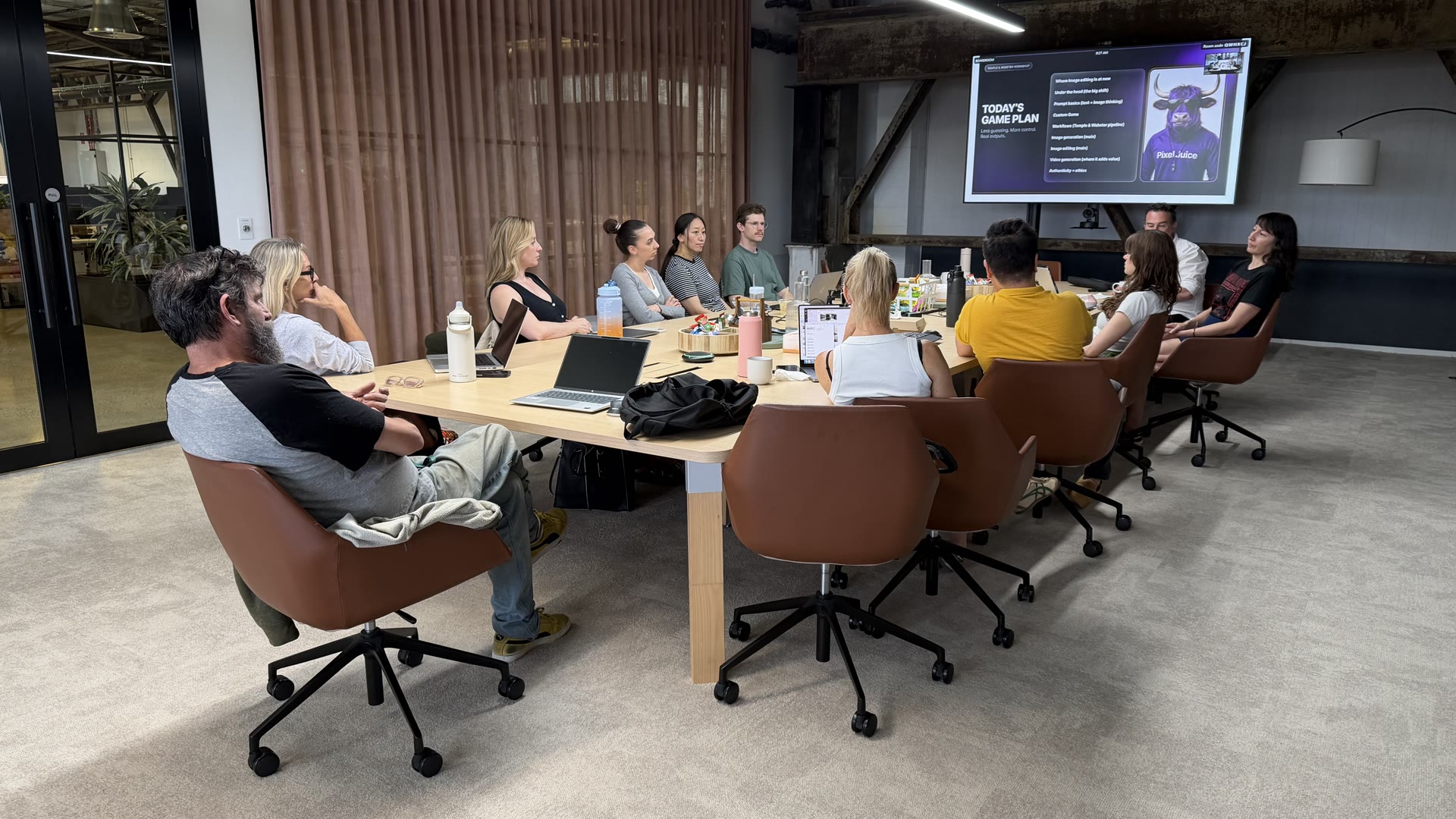 Workshop group seated around a long table facing a presentation screen