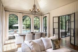 Luxurious living room with arched windows, dining table, sofa, and chandelier.