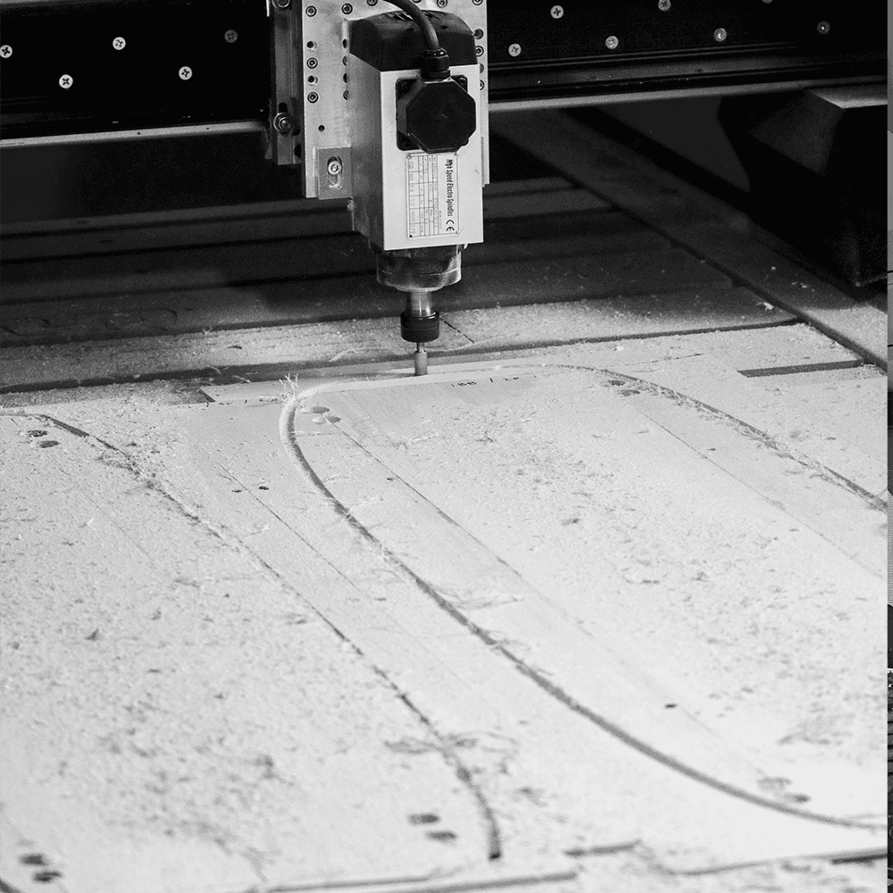 Advanced CNC woodworking machinery in action, showing the detailed engraving and cutting process of a furniture panel in a modern factory setting.