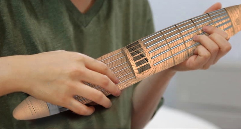 A photo of a person wearing a green t-shirt and playing at a cigar shaped musical instrument.