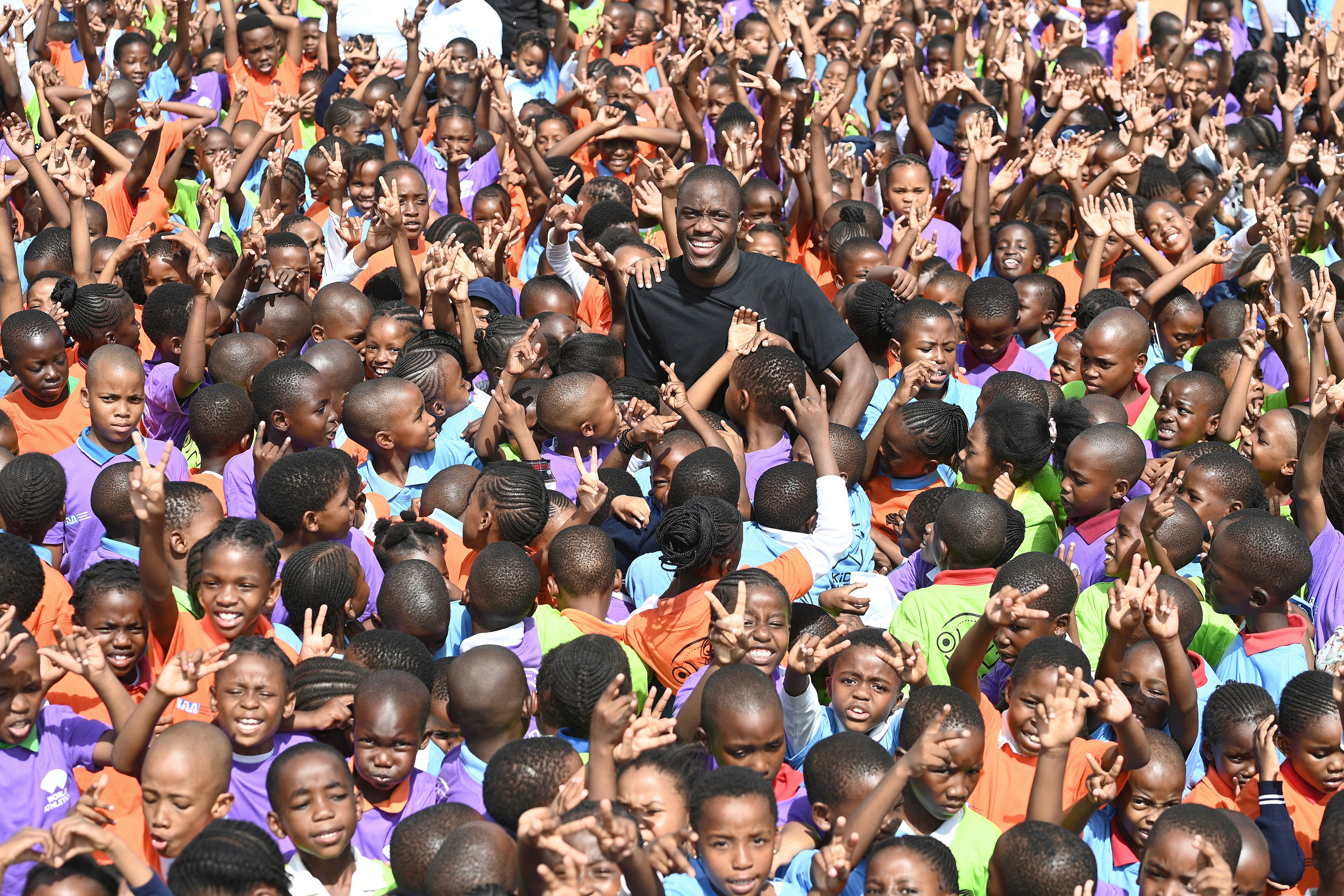 Close-up of a yellow tennis ball sitting on a green court, positioned near the white center line.
