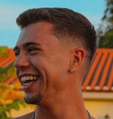 a young man wearing glasses standing in front of a mountain