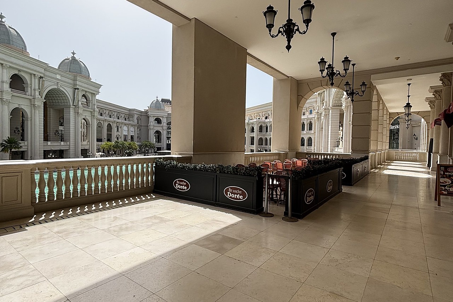 La terrasse d'une Brioche Dorée sous les arcades de Place Vendôme, à Lusail, avec ses tables et ses tabourets rouges : le genre de terrasse où l'on oublie son téléphone au Qatar et où on le retrouve une heure plus tard
