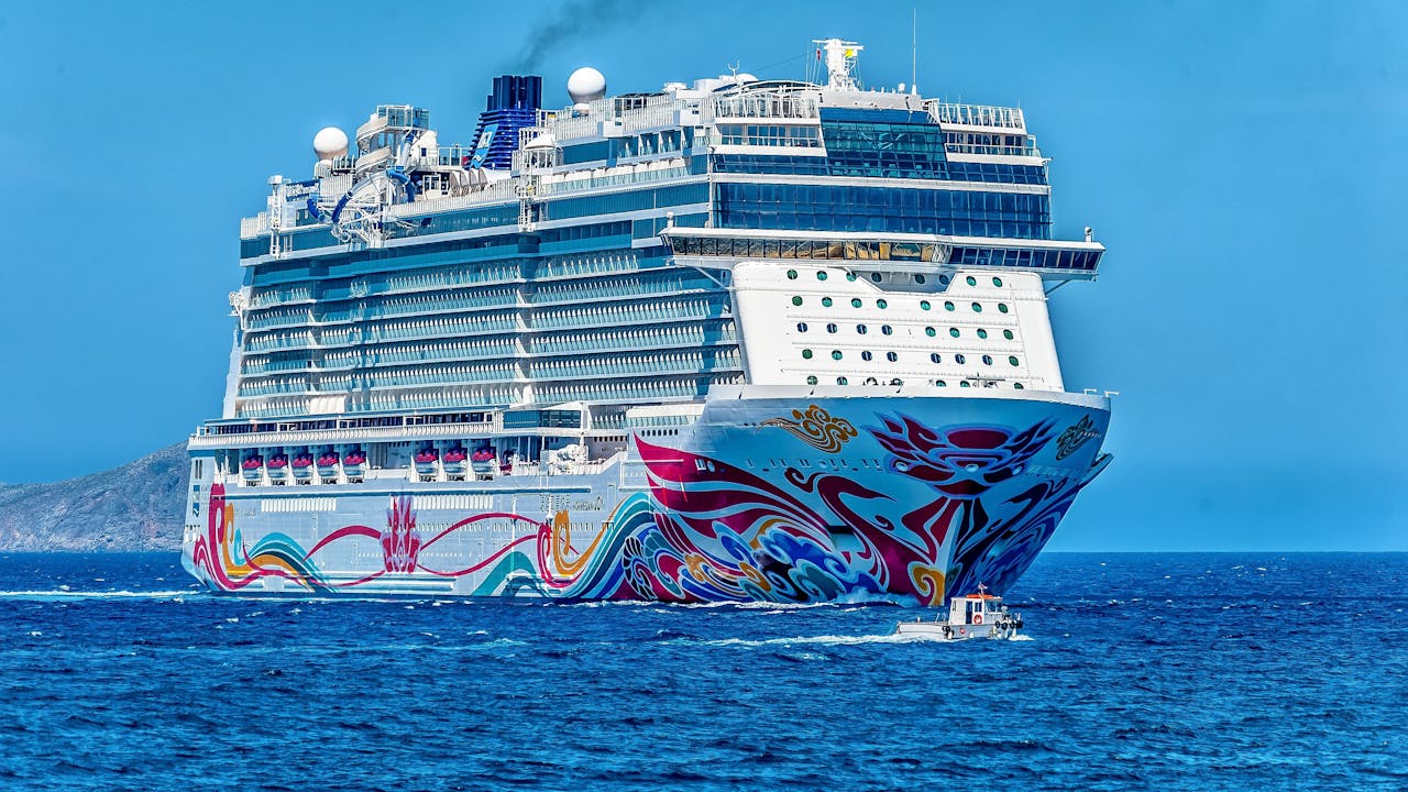 Luxury cruise ship navigating blue waters, showcasing vibrant hull artwork, symbolizing premium cruise transfers from Long Island to New York terminals.