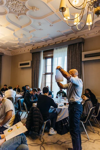 People sitting and standing in a room with tables.
