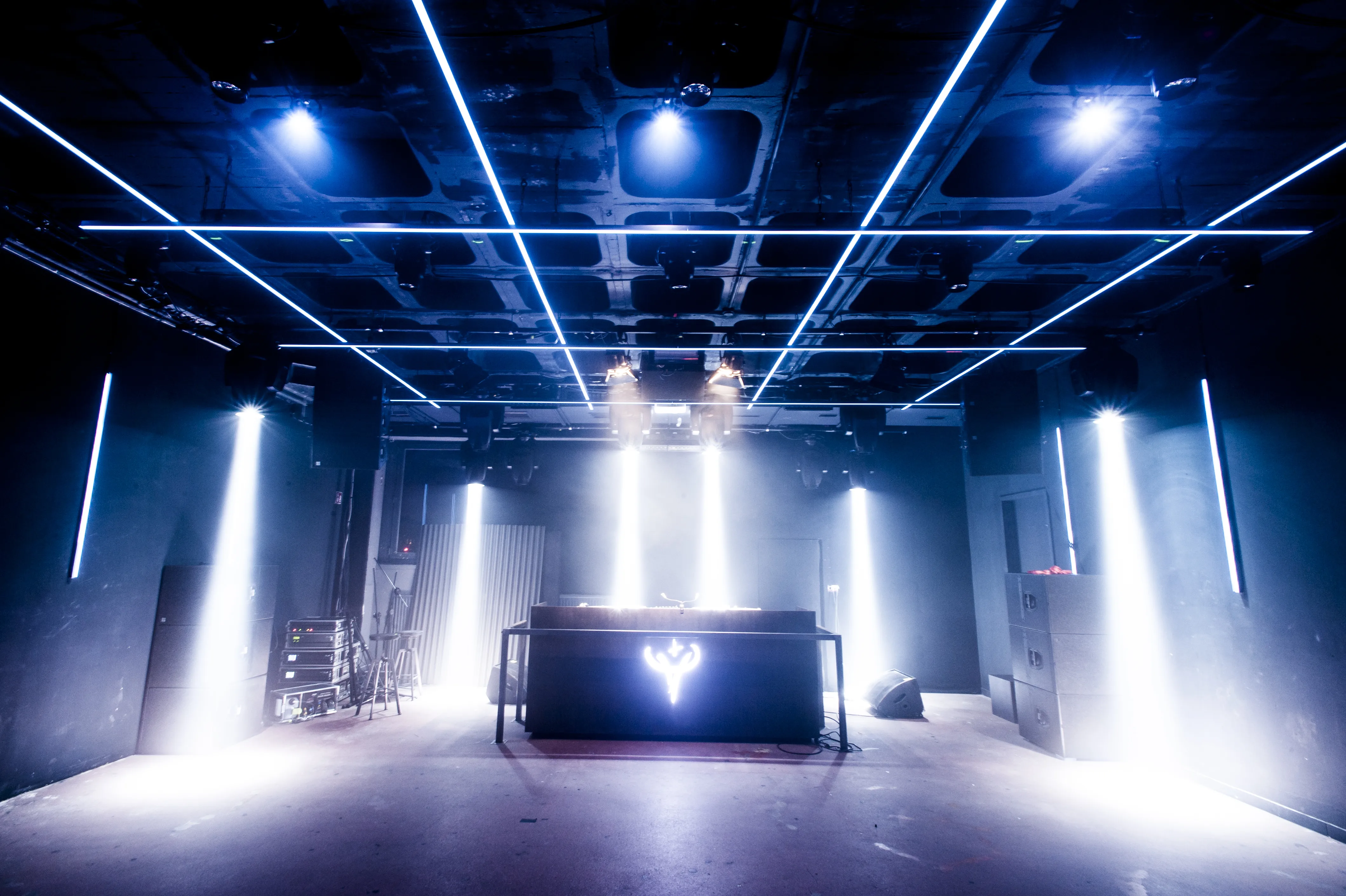 DJ desk with glowing stag logo in blue light beneath crossing LED lines at the Jägermeister Night Embassy.