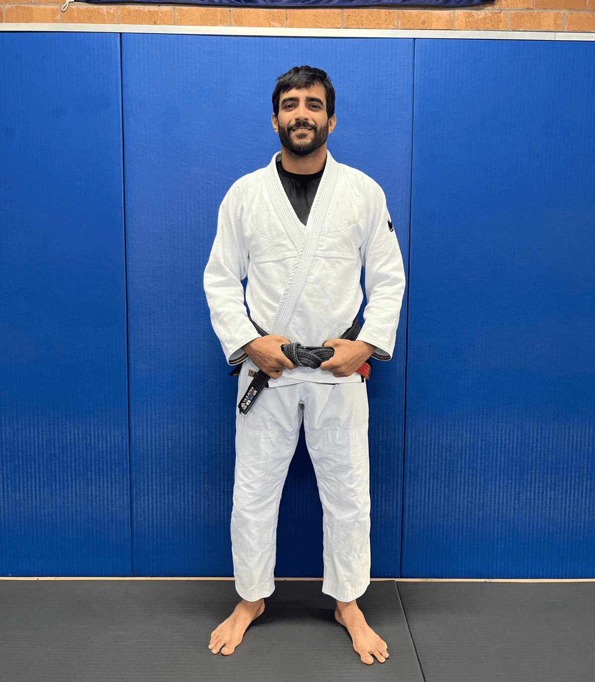 Maria Elisa Thimoteo smiling in her gi, hands folded in front of a gradient backdrop