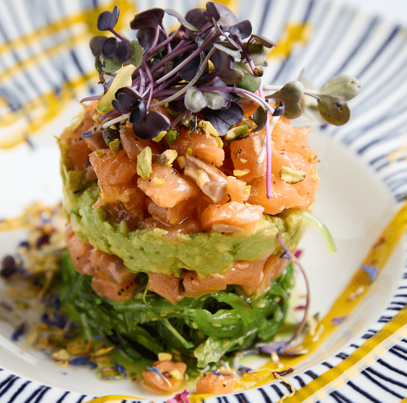 Tartar de salmón ahumado báltico con guacamole casero, coulis de mango anaranjado y pistacho tostado, servido como entrante en Hatillo.