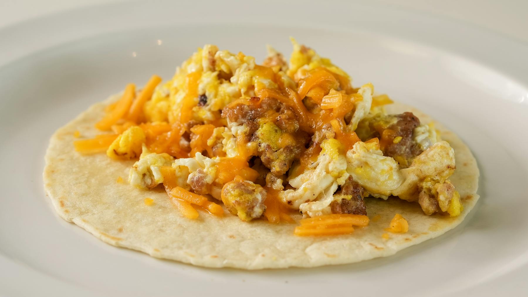 PATATA TACO A savory blend of hearty potatoes, fluffy eggs, melted cheese, and crisp onions