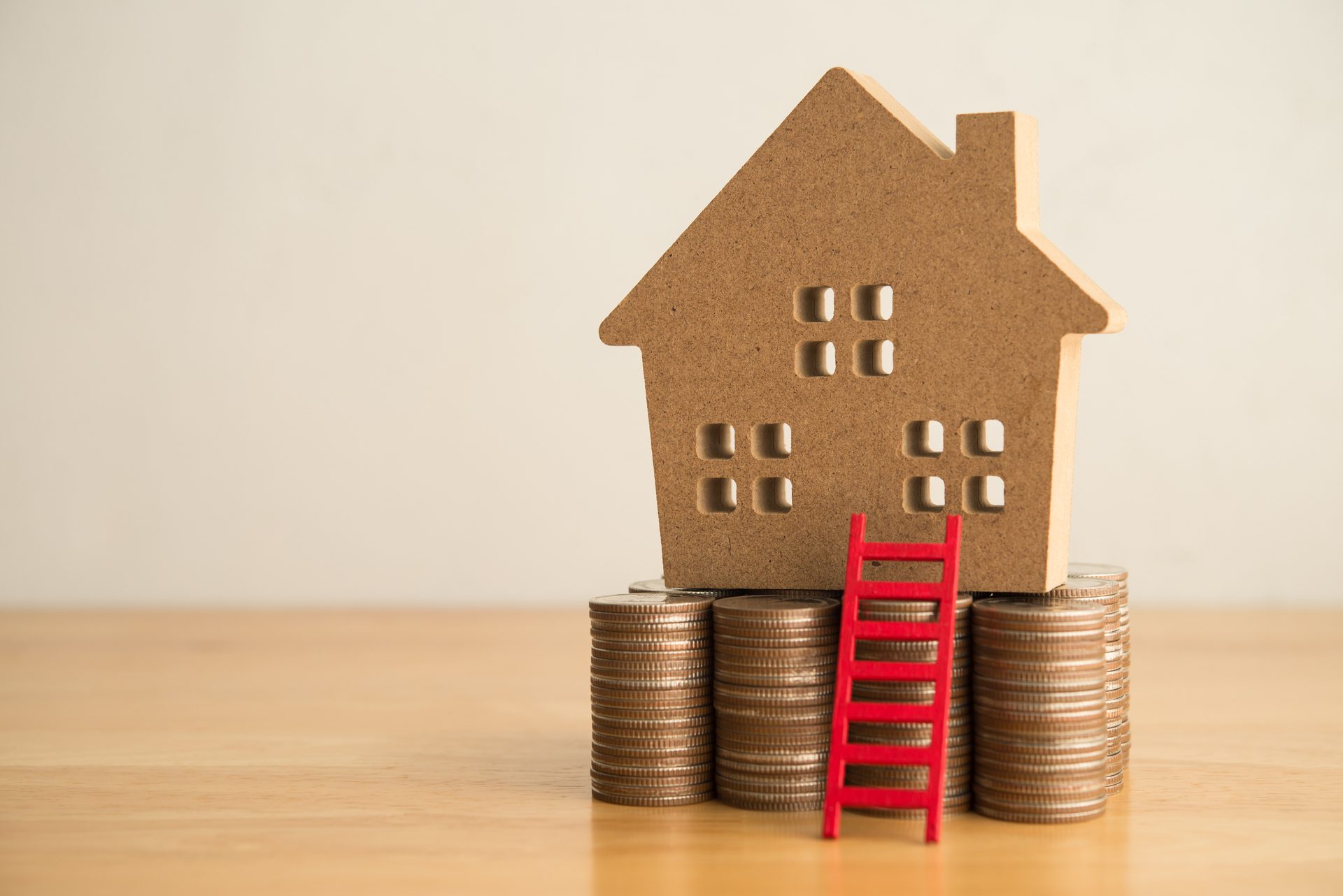 Model house on coin stacks with red ladder