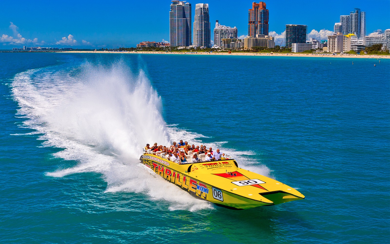 Speedboat with tourists on Miami sightseeing tour, city skyline in background.