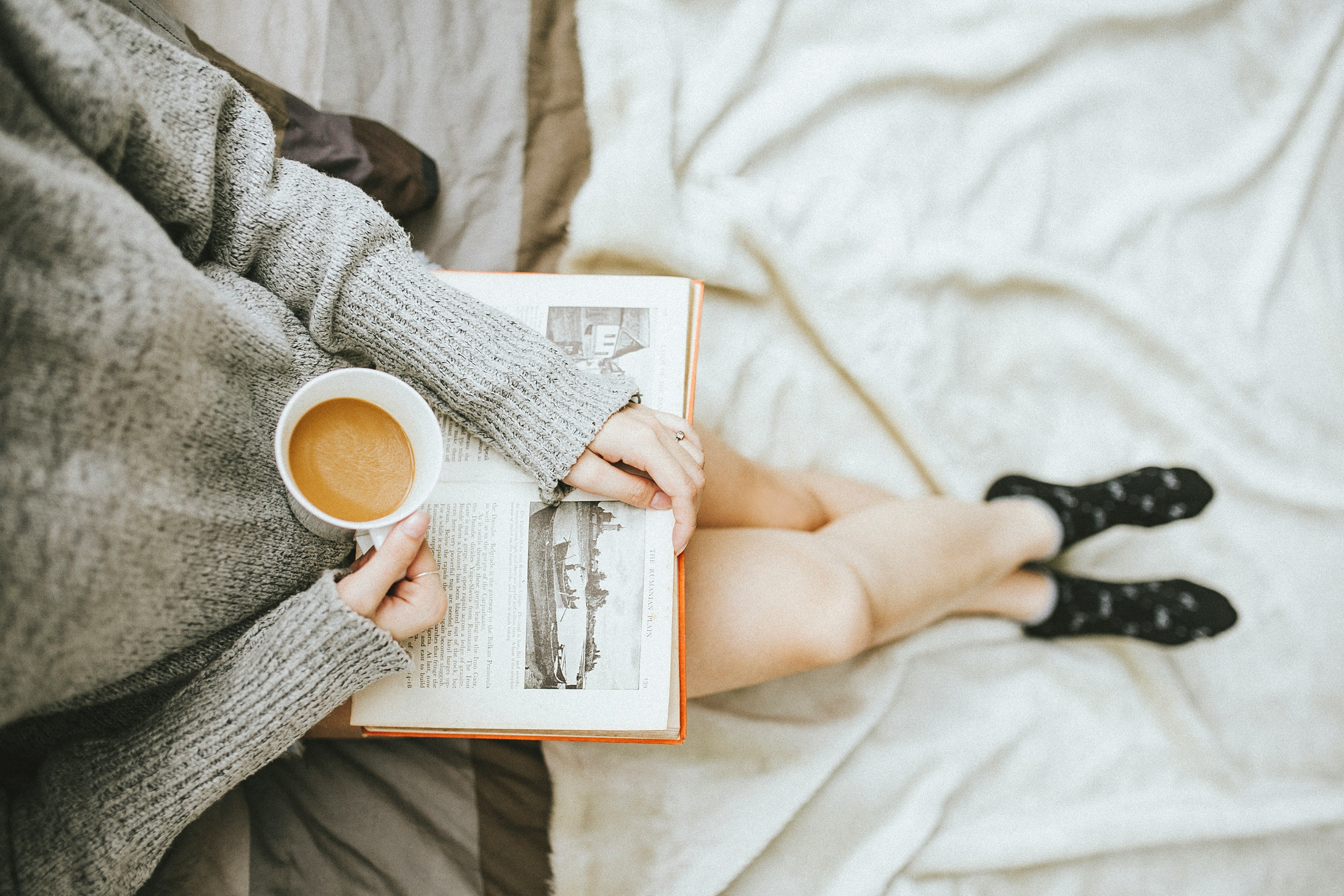 A woman reading a book and drinking tea