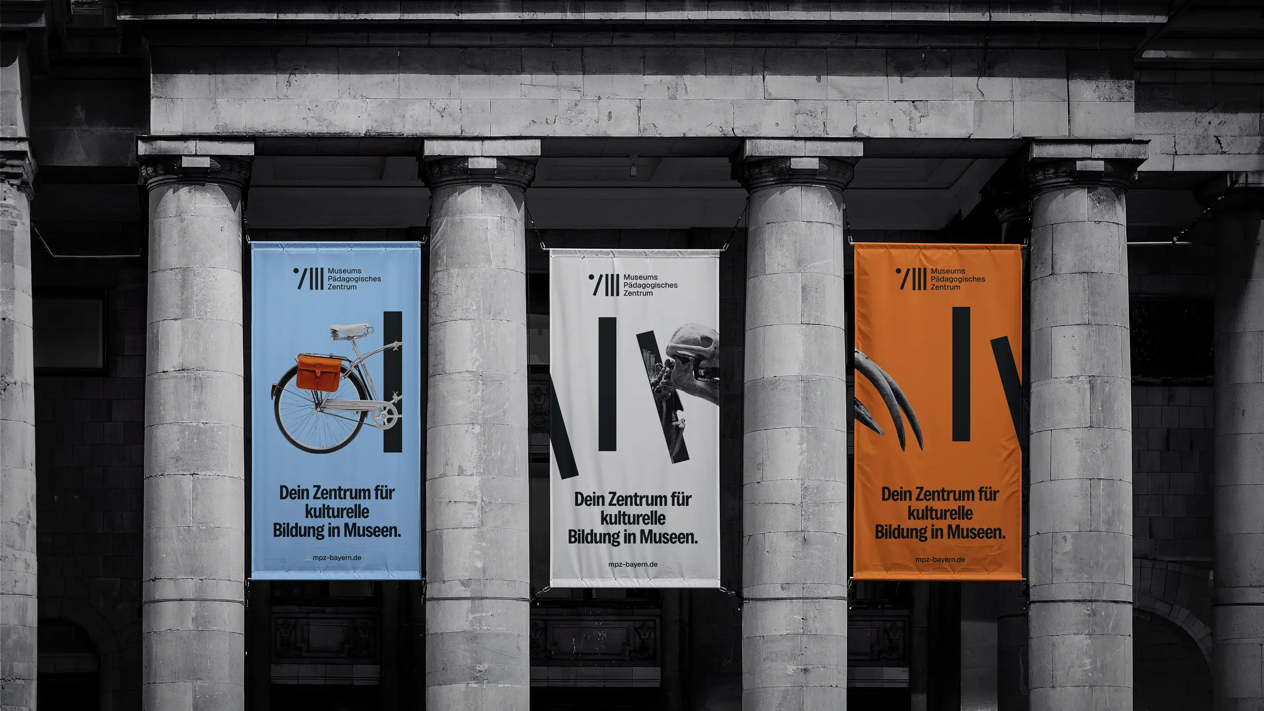 Drei MPZ-Banner zwischen Säulen mit Fahrrad, Logo und Vogelschädel-Motiv
