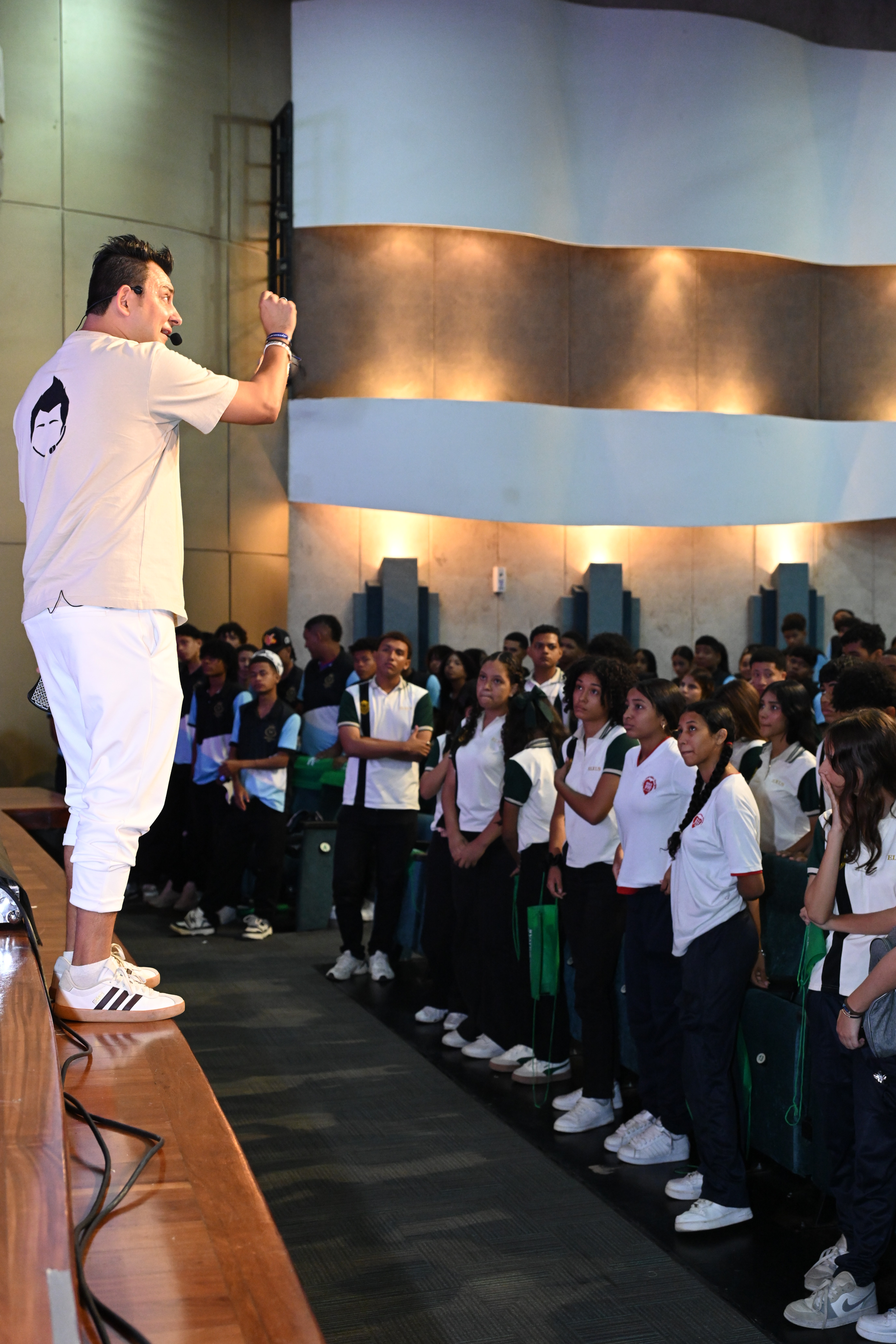 Jorge Baena en el escenario hablando con energía frente a un público de estudiantes, durante una conferencia