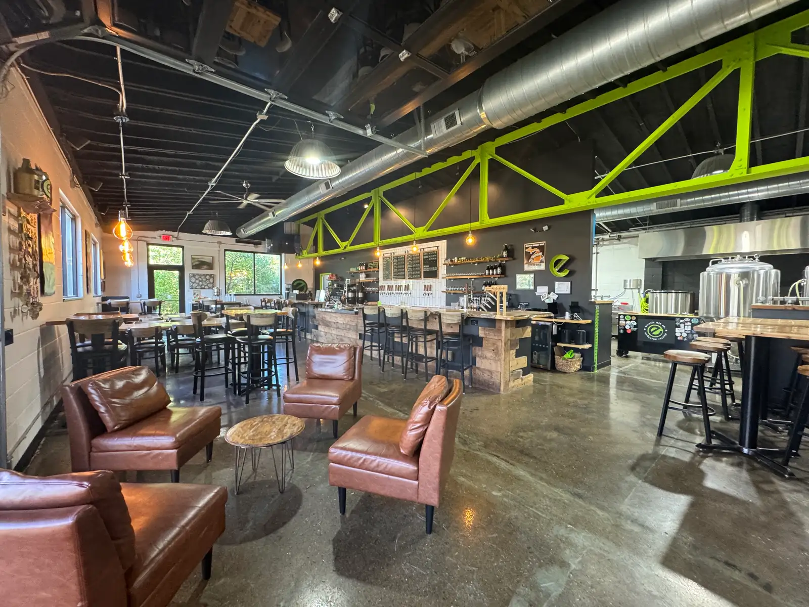 interior of erratic ale company, with four brown leather chairs in the foreground facing each other.