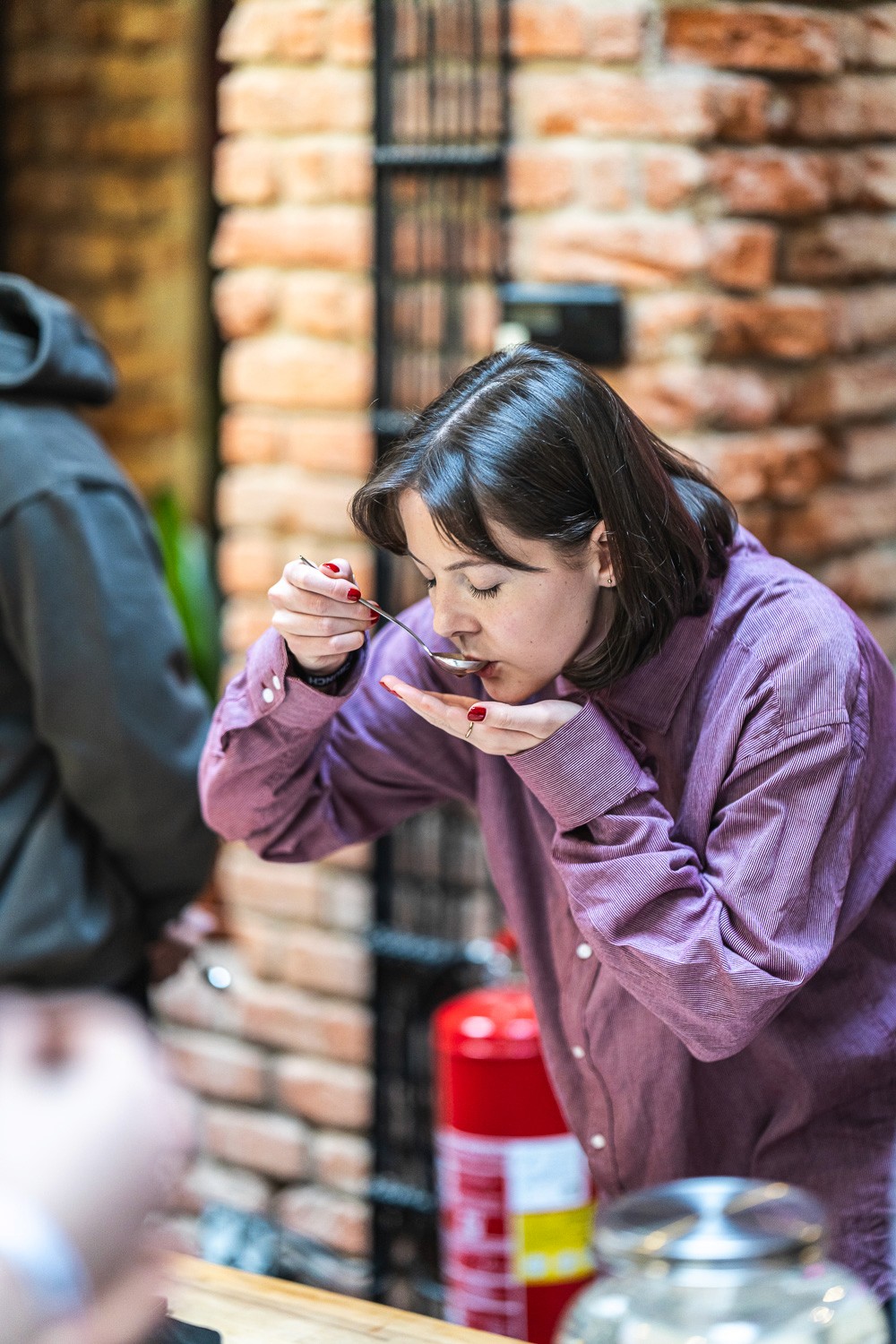 Participant tasting coffee during a hands-on cupping workshop at a conference.
