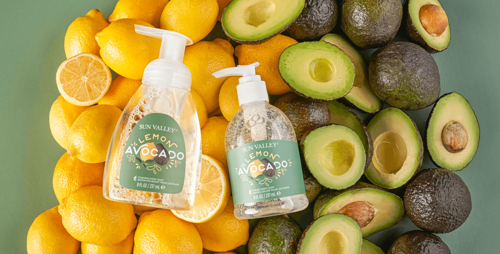 Person wearing black clothing carrying a black tote bag with a green globe-like geometric symbol, standing against a concrete wall in sunlight and shadow.