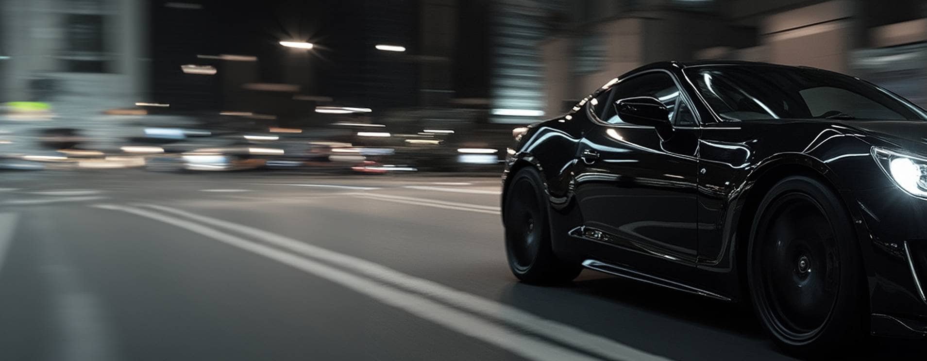 Une photo en contre-plongée avec flou de mouvement d'une voiture de sport noire et élégante roulant sur une rue de la ville la nuit, avec les lumières en arrière-plan qui défilent.