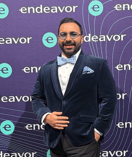 A young person with long, wavy hair sits in front of a plain background, looking directly at the camera.