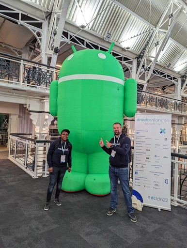 Deux personnes devant la mascotte Android