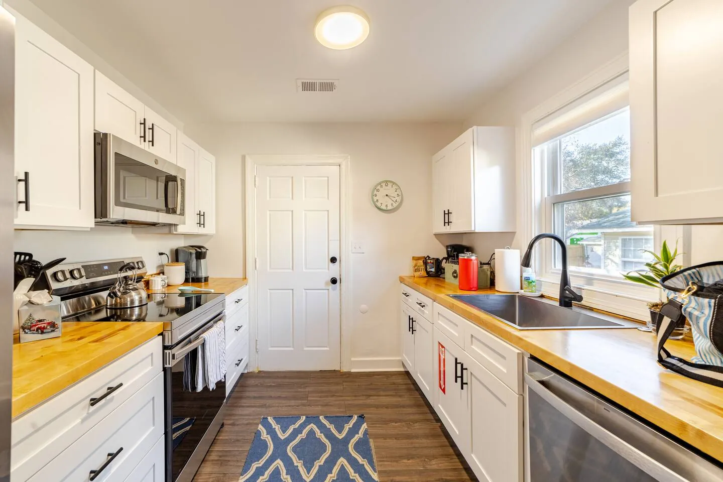 Galley kitchen with butcher-block counters, white cabinets and stainless appliances