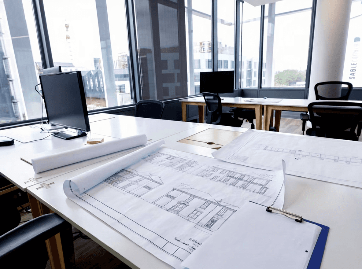 Architekturpläne und Bauzeichnungen auf einem Schreibtisch im modernen Planungsbüro in Wien.