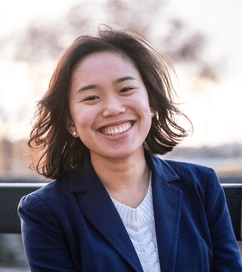 Une jeune femme regarde la caméra en souriant.