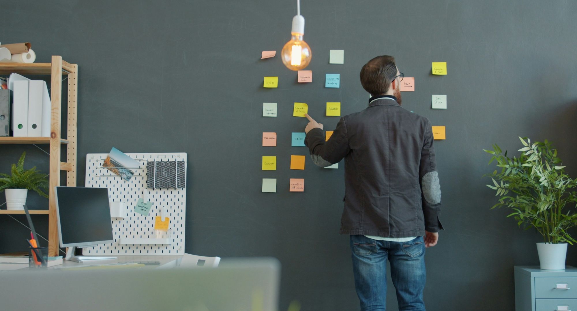 homem que planeia olhando para pequenos papeis quadrados grudados na parede