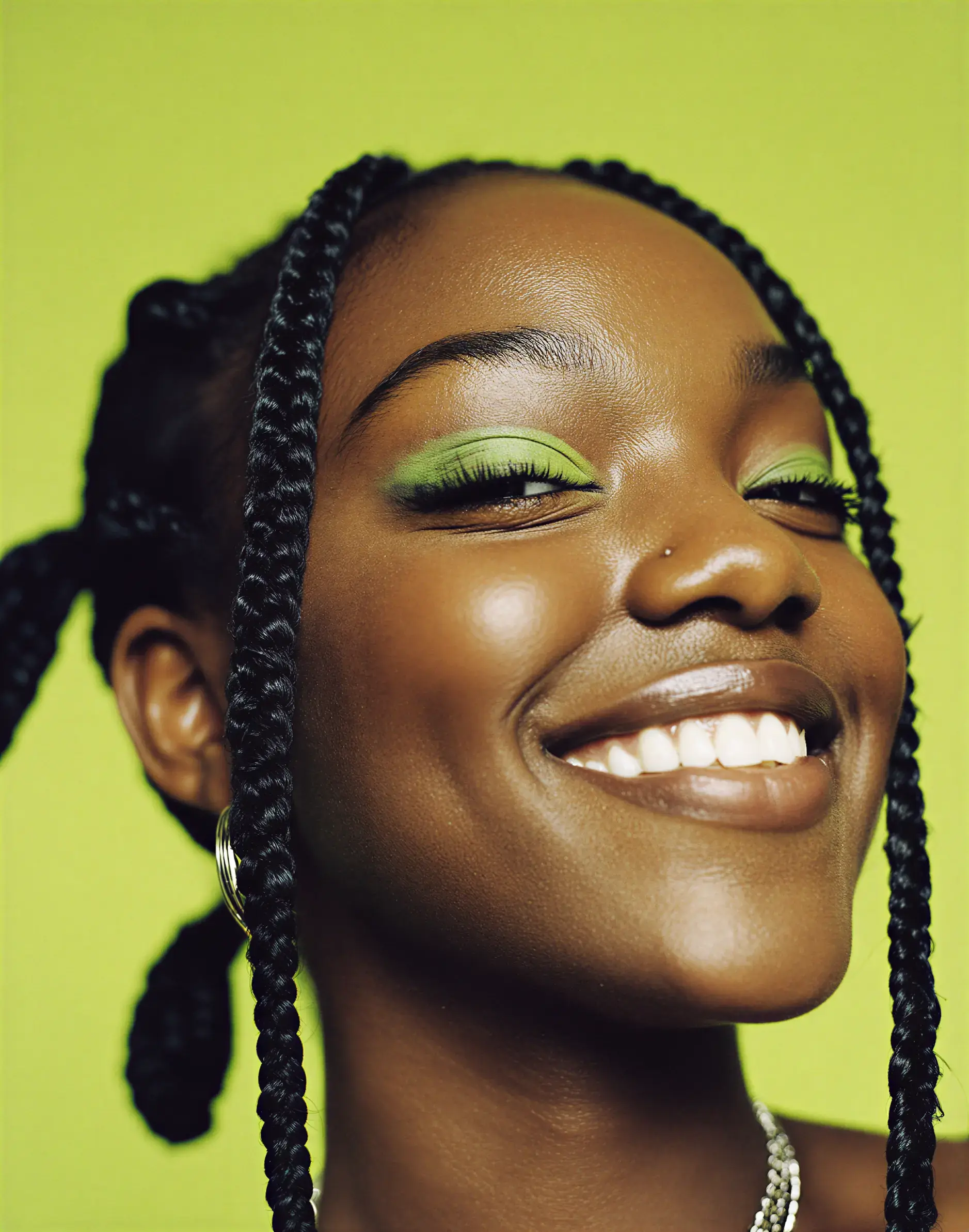 Close-up of a smiling woman with bright green eyeshadow against a vibrant background