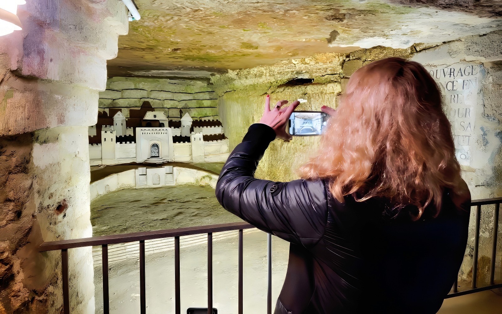 女士用智能手机拍摄巴黎地下墓穴模型的照片。