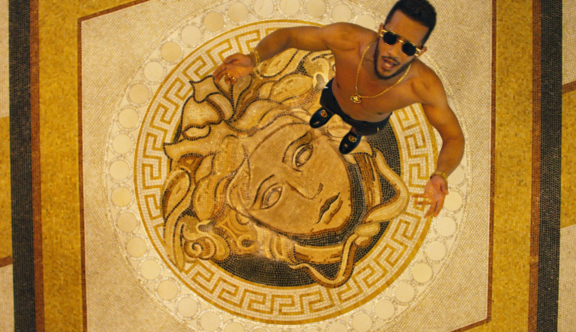 Black-and-white party photo of a smiling man in a check blazer among a crowd.