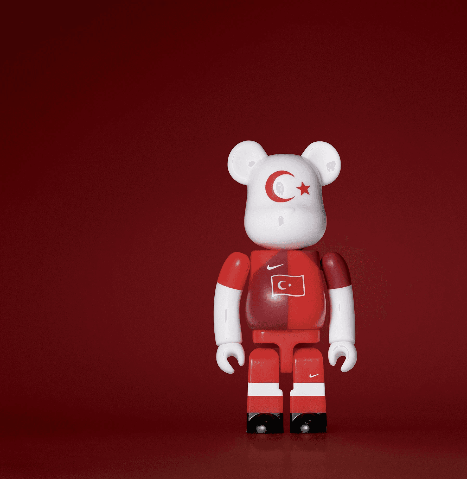 A single 3.5” tall Bre@rbrick/Nike toy created to commemorate the 2006 Turkish World Cup football team. The toy is painted to appear in the Turkish football kit and stands in the center of the frame in front of a dark red background.