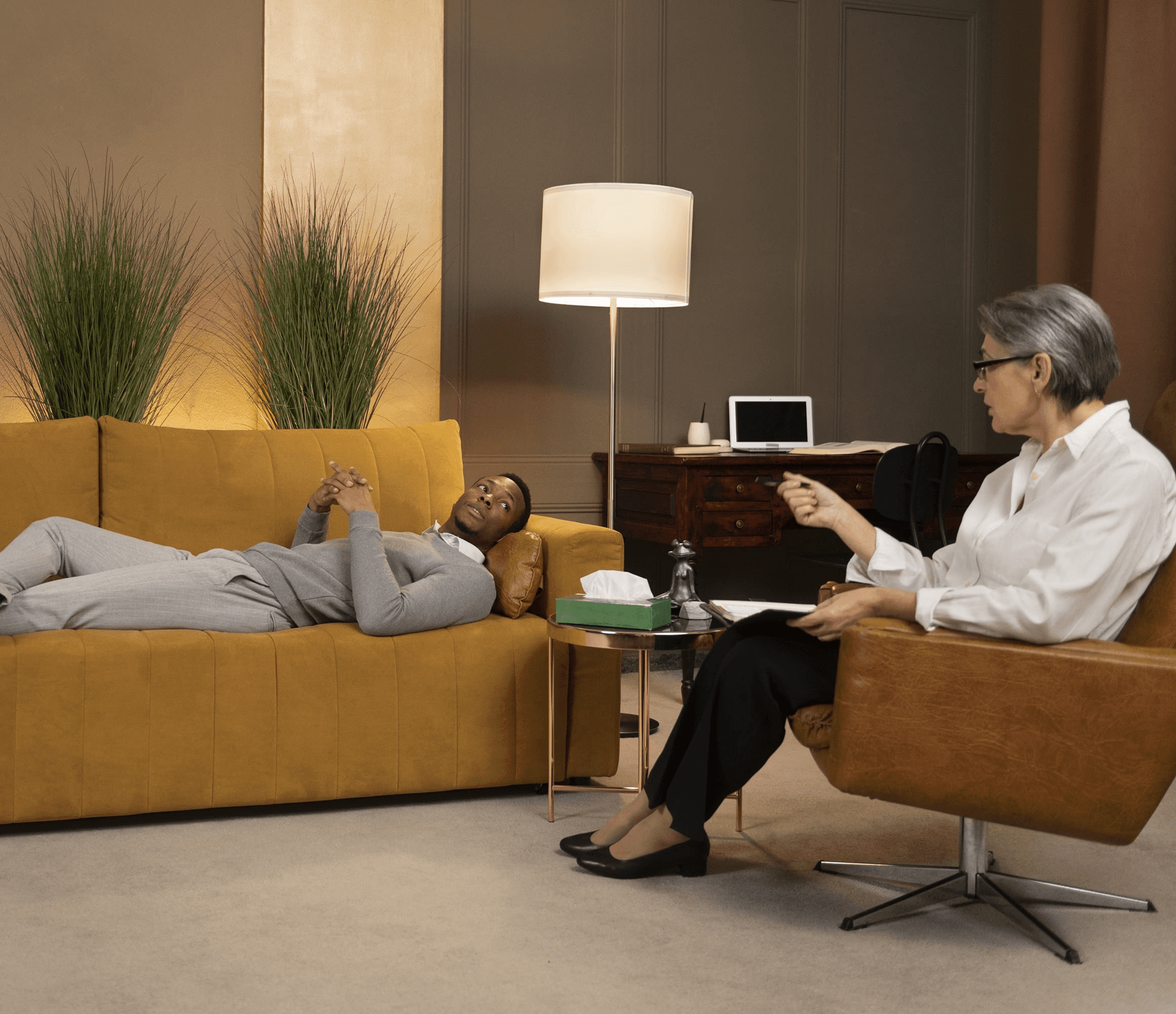Psychologist talking with client lying on sofa during therapy session