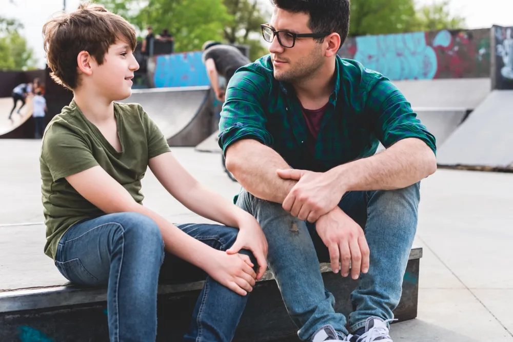 Adult and child talking to each other at a skate park
