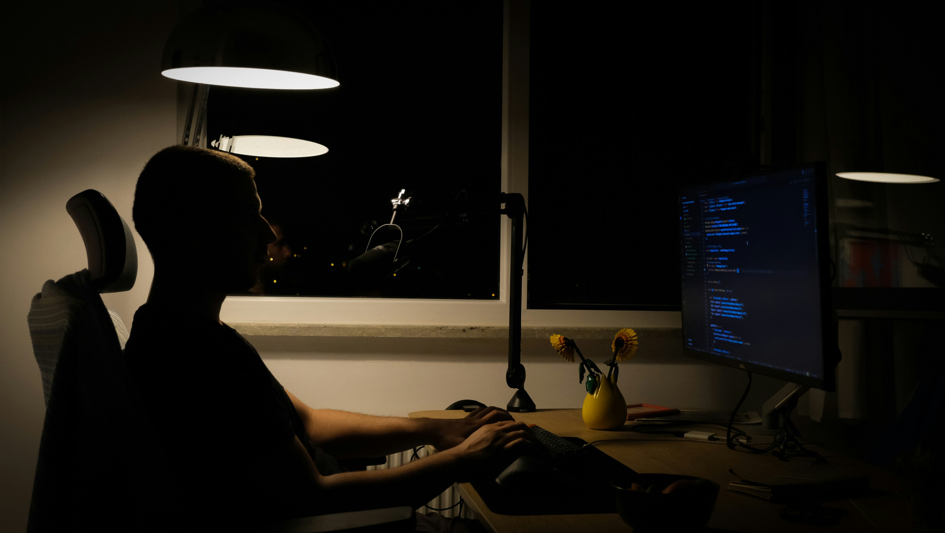 a man sitting in front of a computer in a dark room