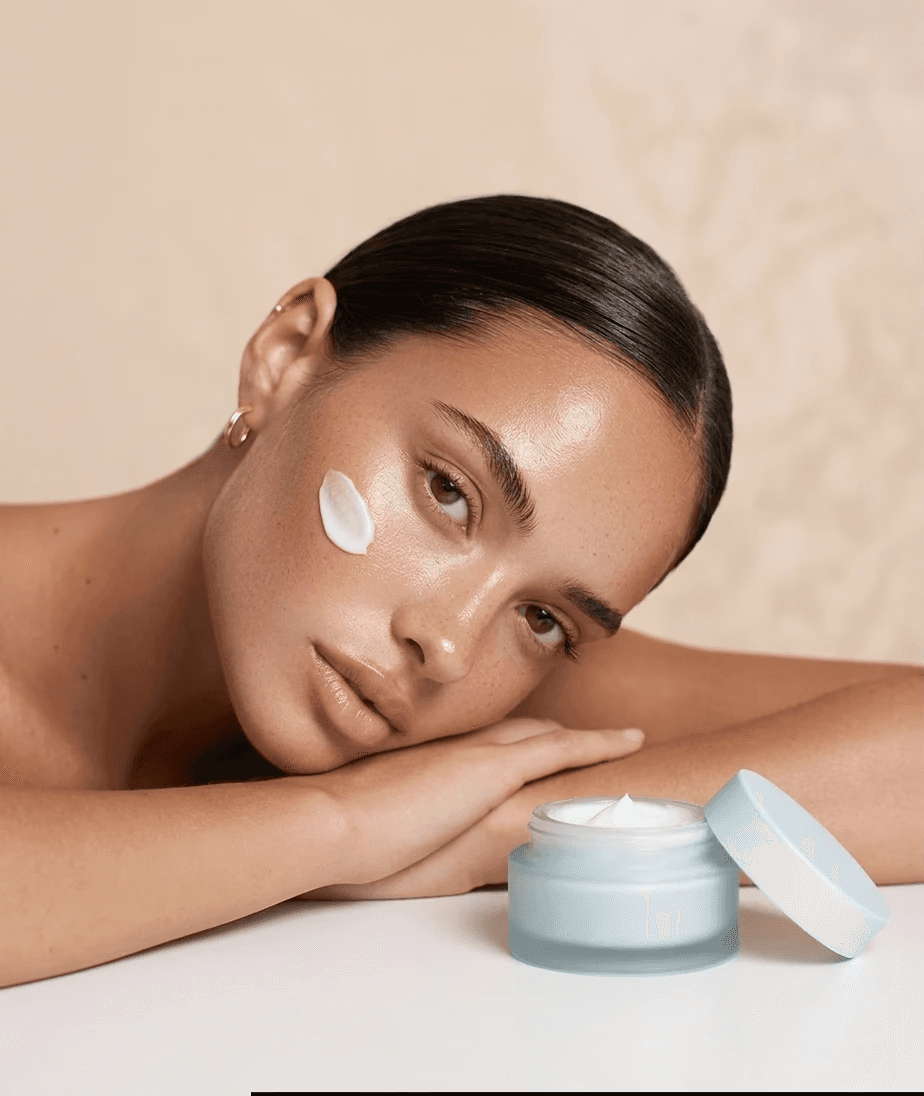 Model with face cream swatch next to open moisturizer jar