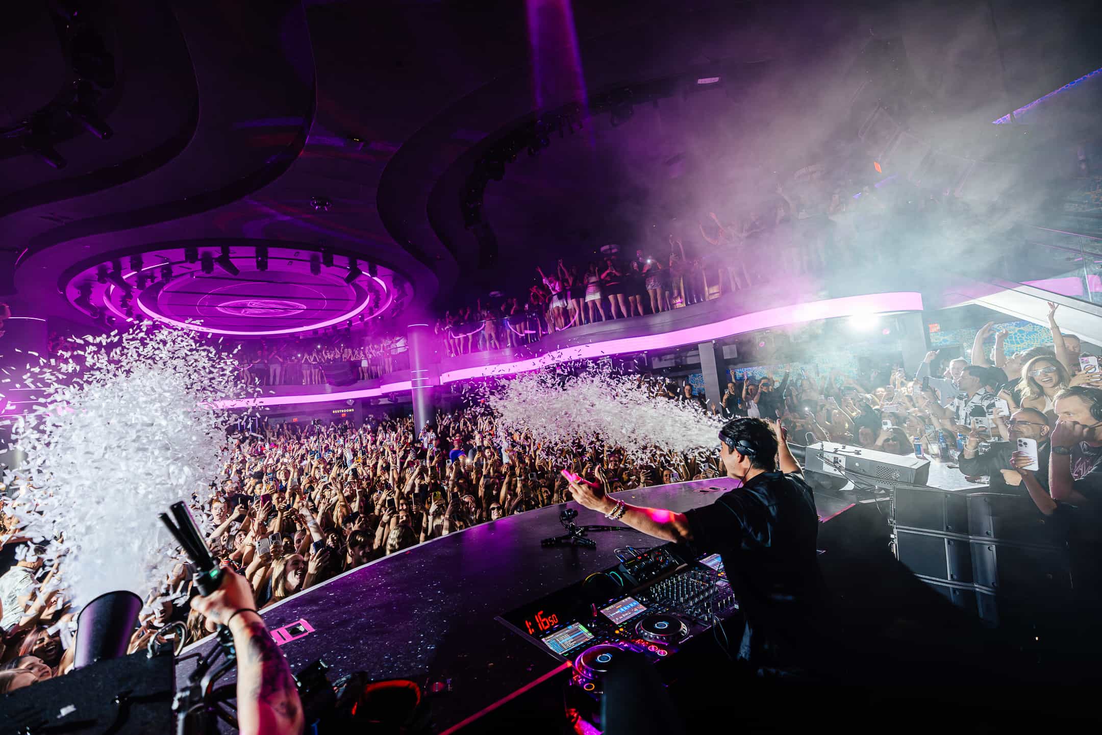 John Summit performing at LIV Las Vegas nightclub with confetti blast and packed crowd across multi-level venue, photographed by A World Away