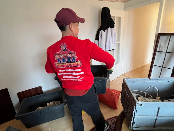 Mitarbeiter im roten Shirt räumt Kisten aus einer leergezogenen Wohnung