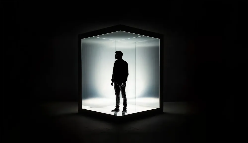 Silhouetted Person in Illuminated Glass Cube 
