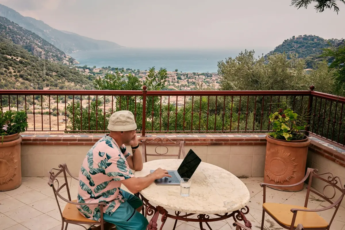 A laptop on a beach table with a view of the Mediterranean Sea, representing remote work opportunities in Spain for digital nomads