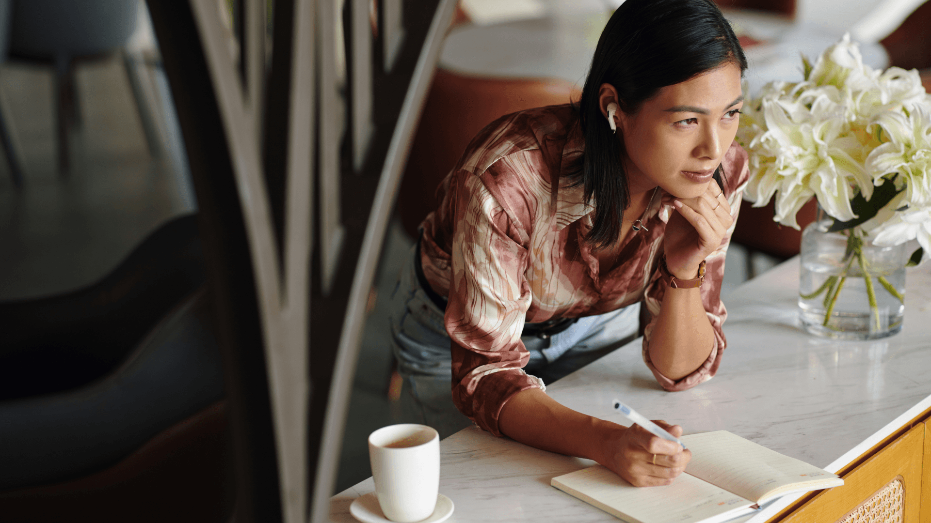 A winding road cuts through rocky terrain, surrounded by patches of green grass and illuminated by sunlight.